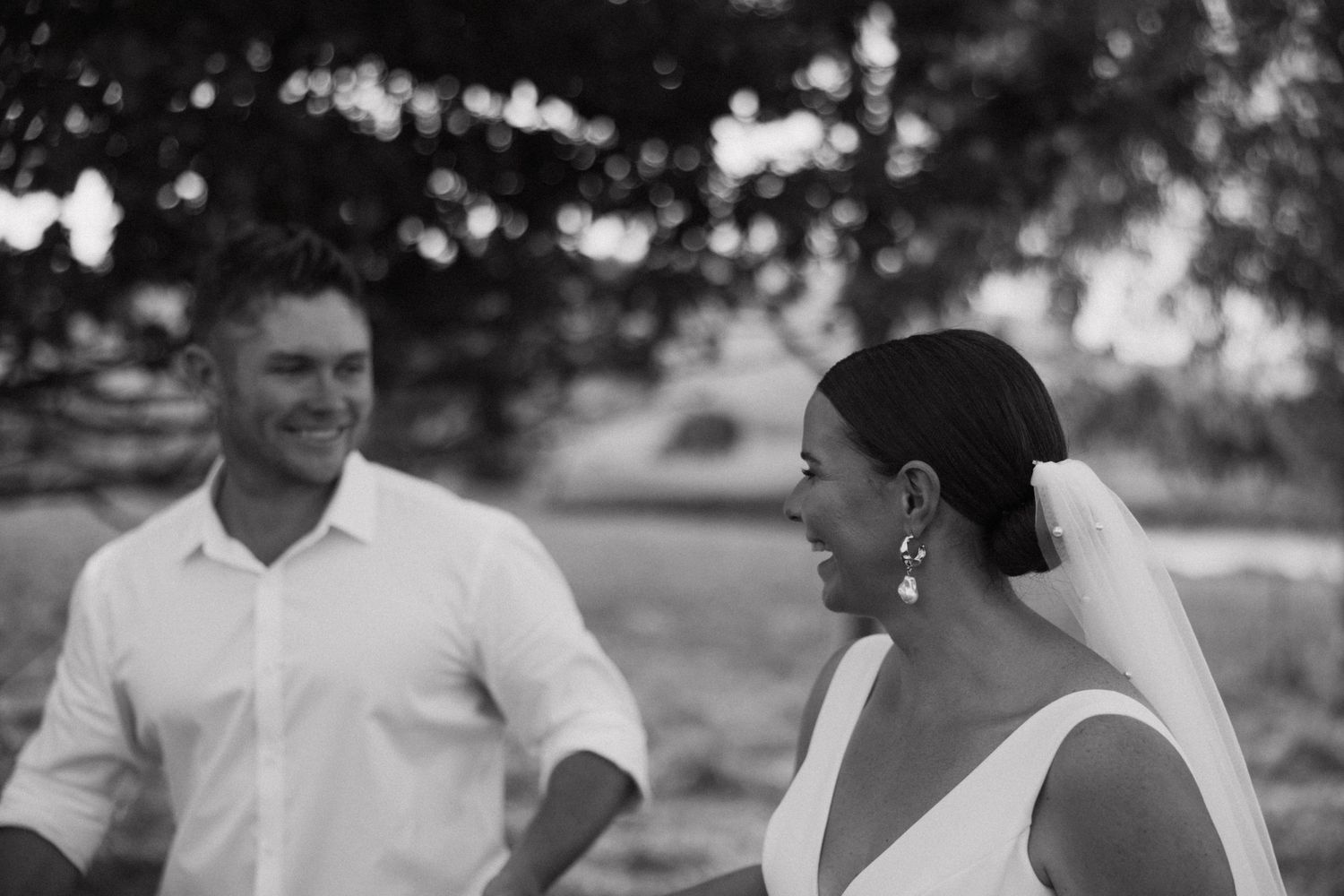 A candid black and white photo of a bride and groom laughing together during their wedding.