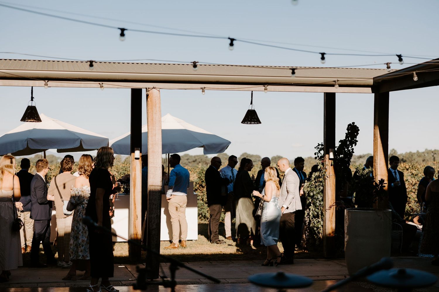 Guests gather under a covered outdoor patio at sunset with mountain views in the background.