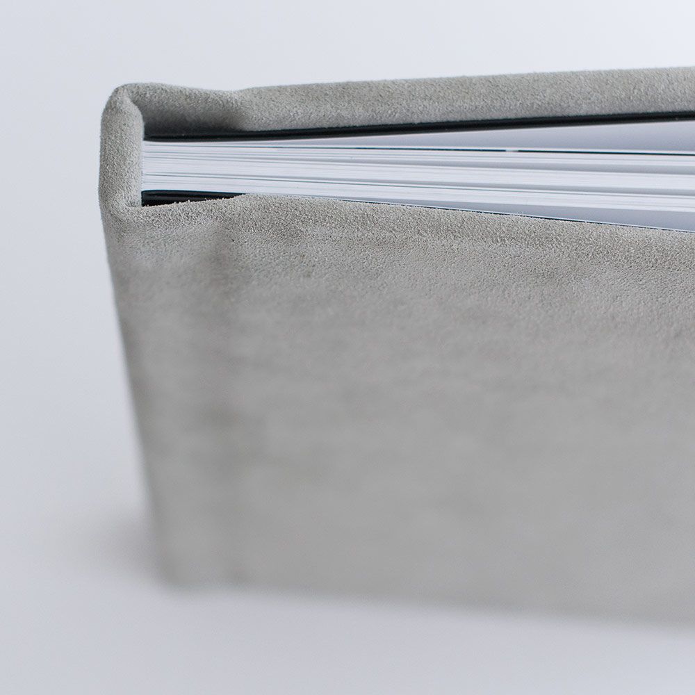 Close-up view of a gray leather photo album spine showing layered pages.