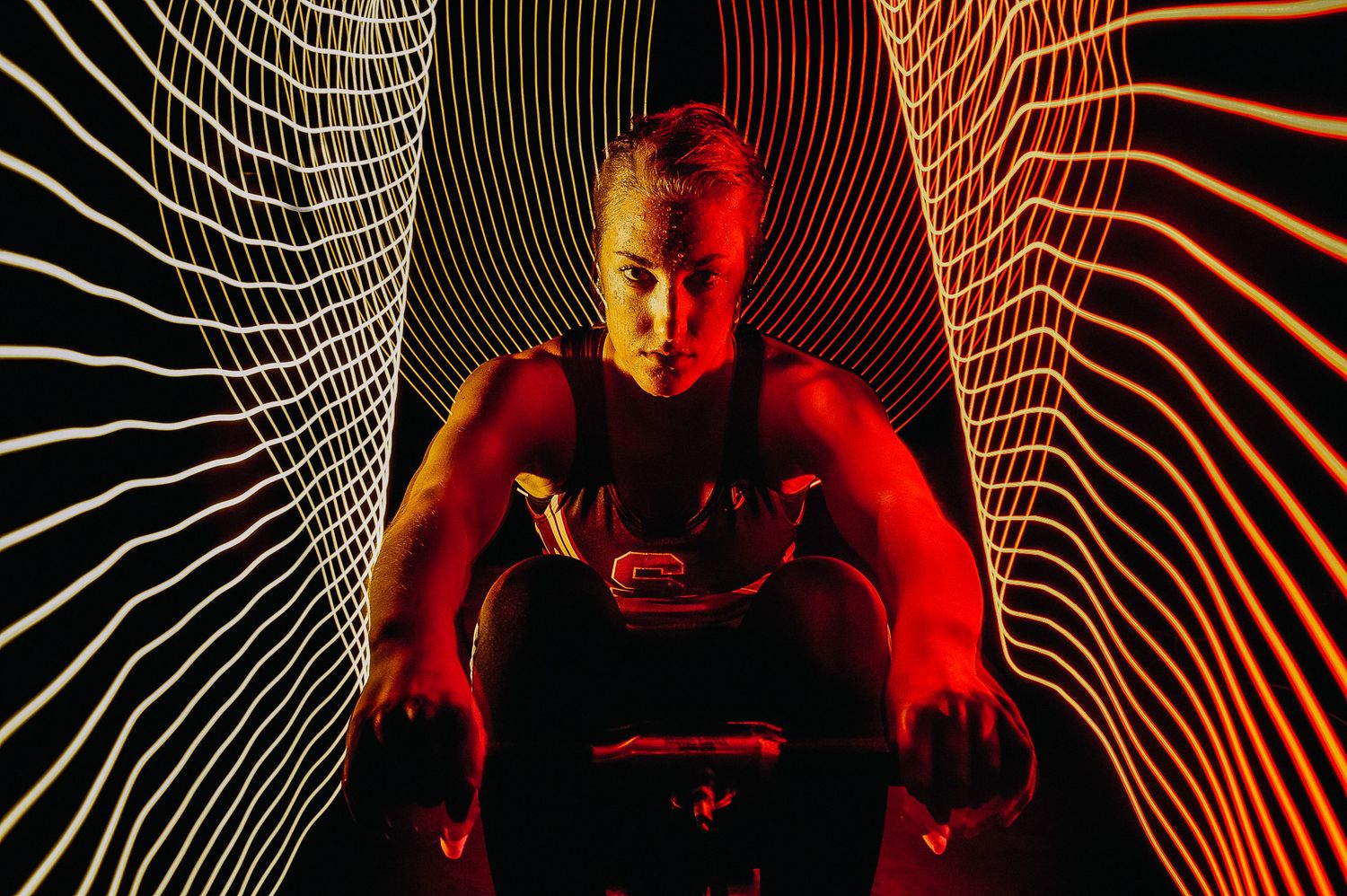 Dark artistic portrait with glowing wavy light trails creating dynamic patterns against red illumination.