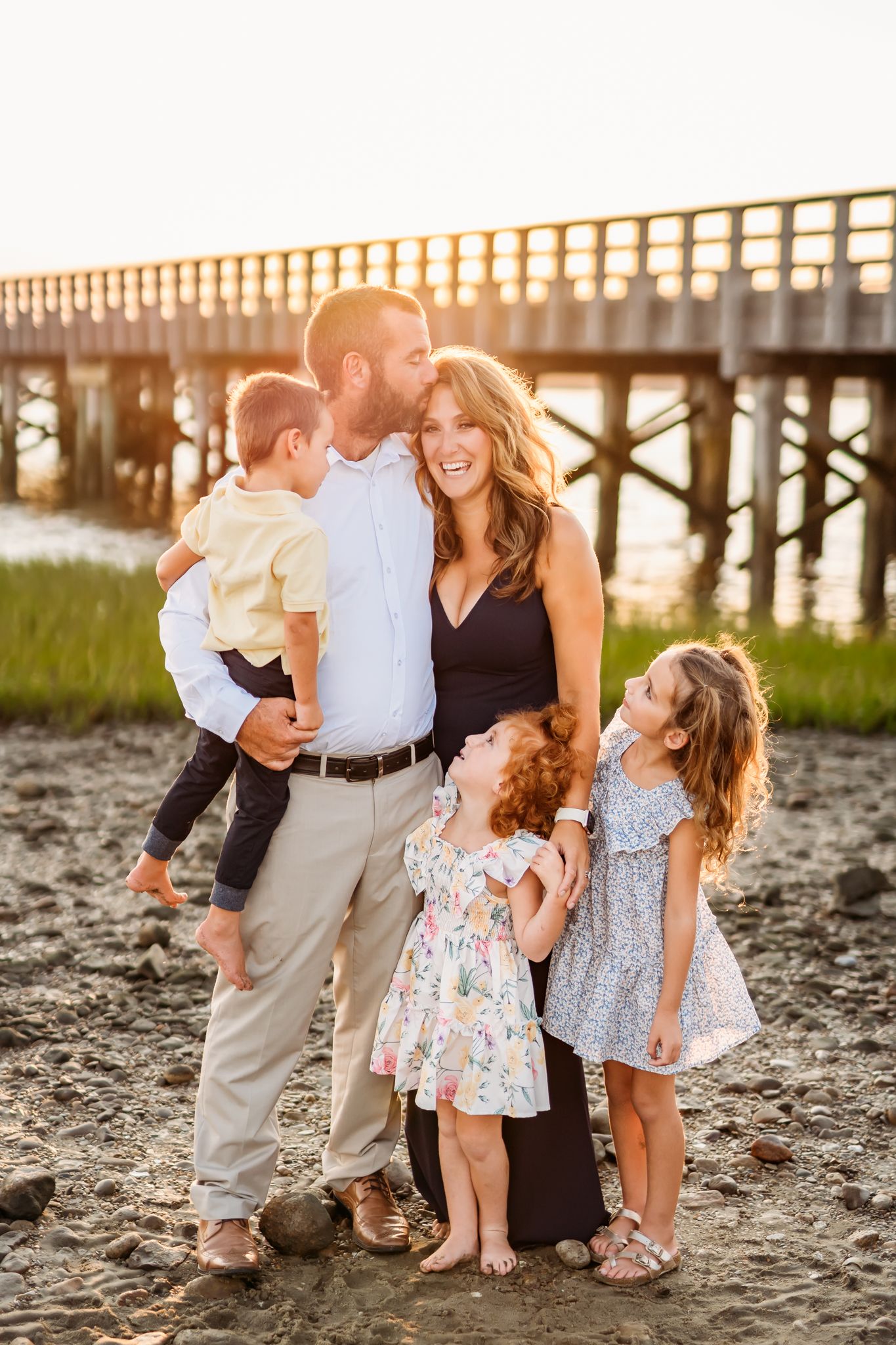 Family enjoys a sunset moment together on the beach with Powder Point Bridge in Duxbury in the background.