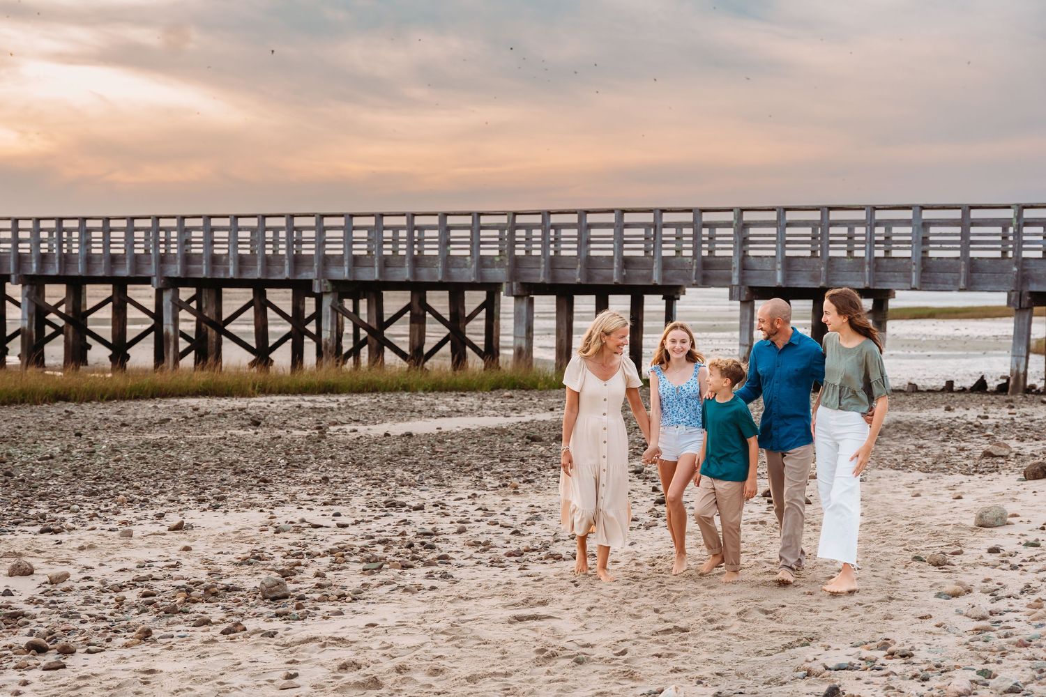 Group walking together on beach at sunset near wooden pier on South Carolina coast.