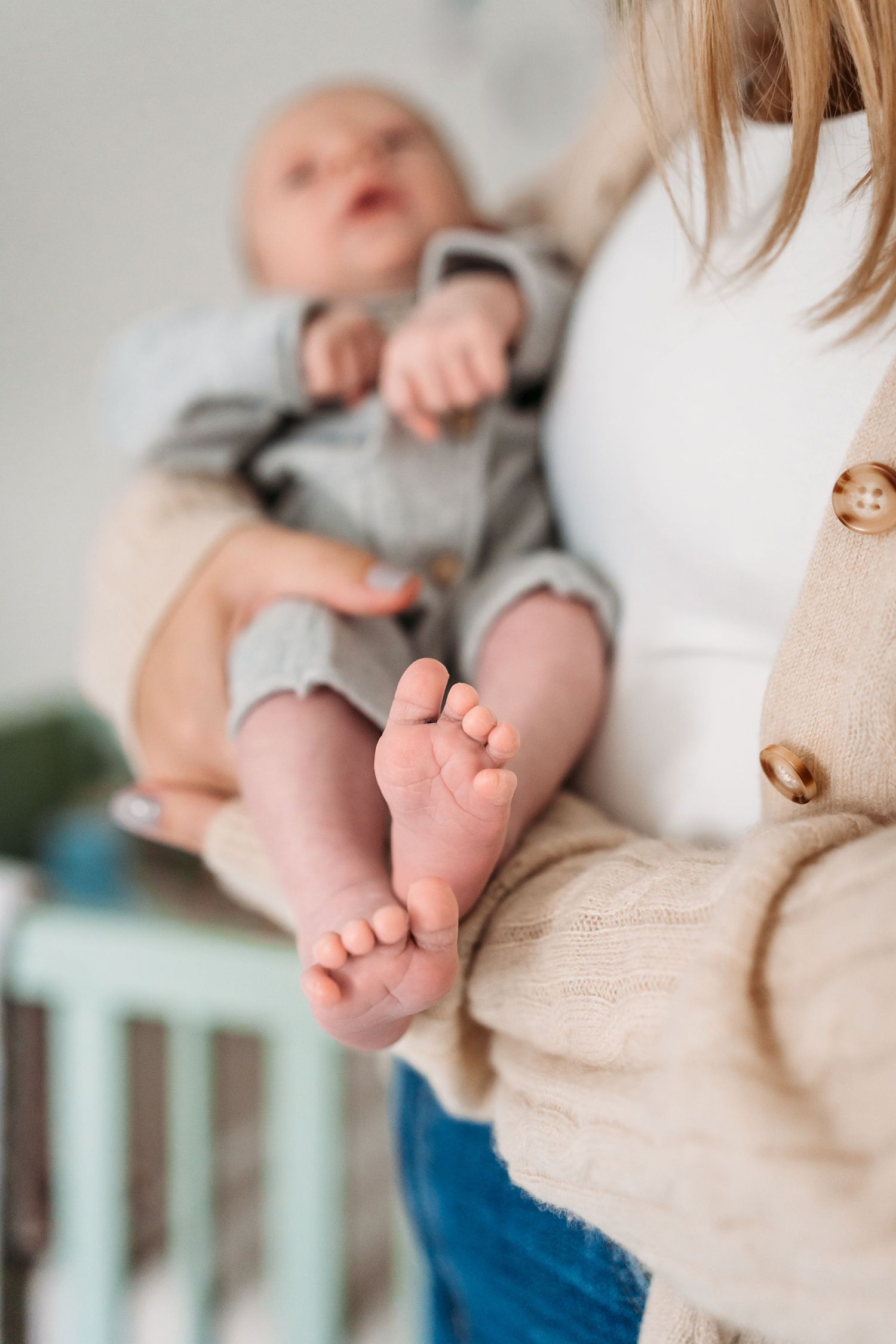 Close-up view of a baby's tiny feet while resting against someone in casual attire.