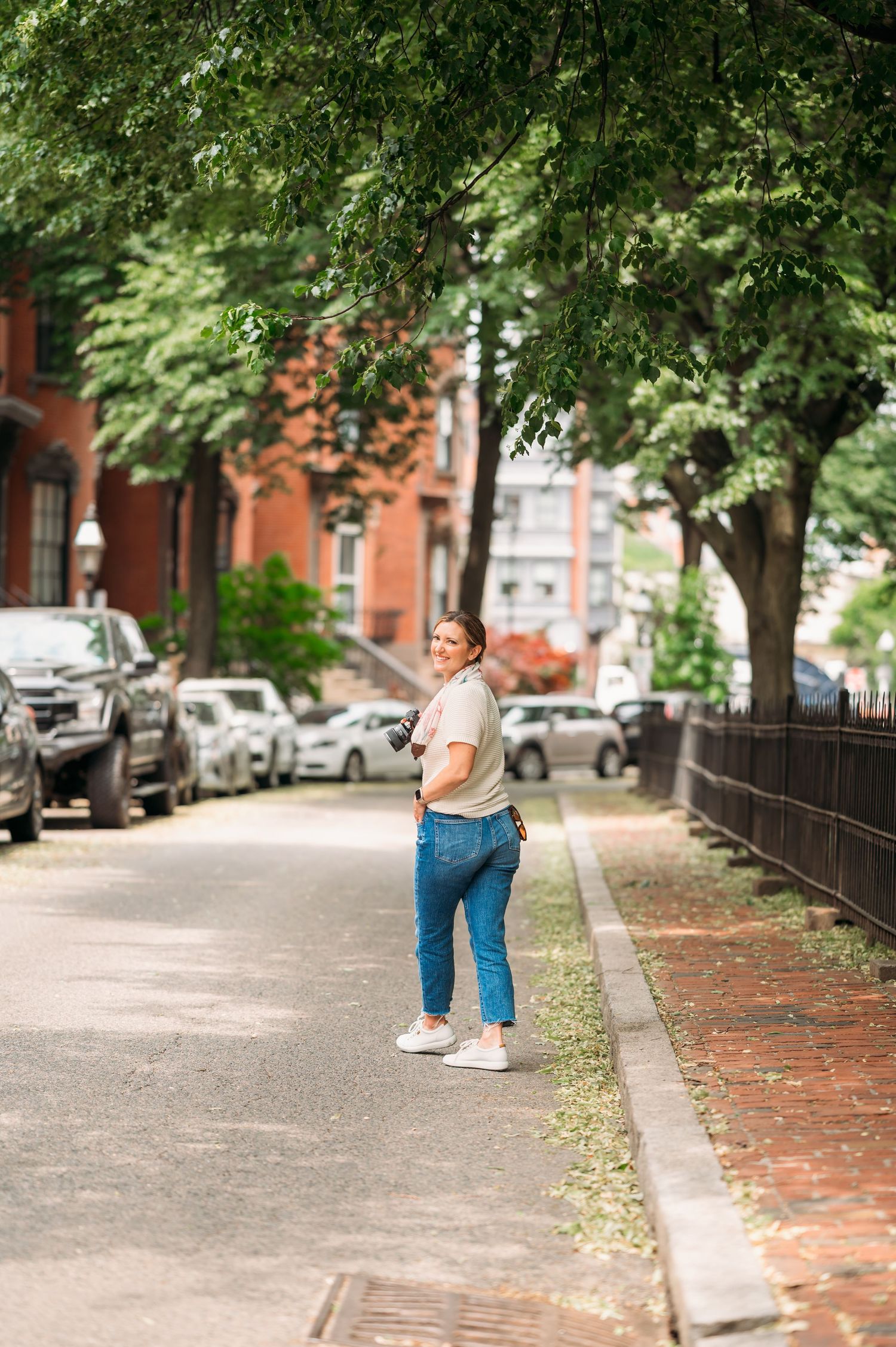 A view down a tree-lined urban street with brick sidewalks and parked cars creating a peaceful city atmosphere.