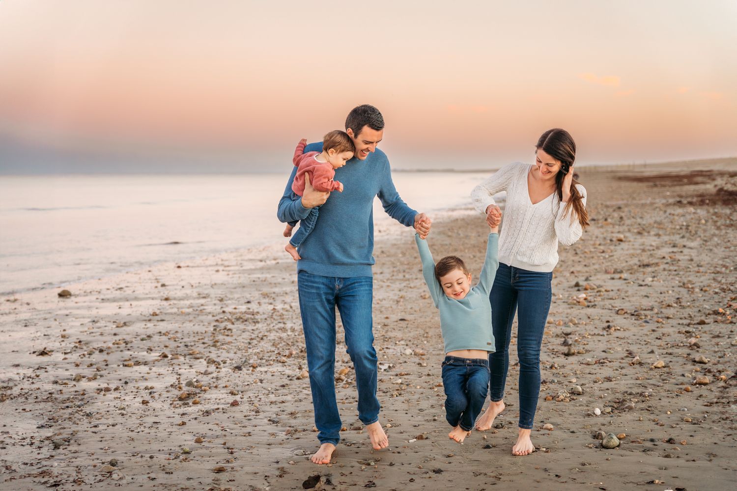A family enjoys a stroll together along a serene beach during sunset.