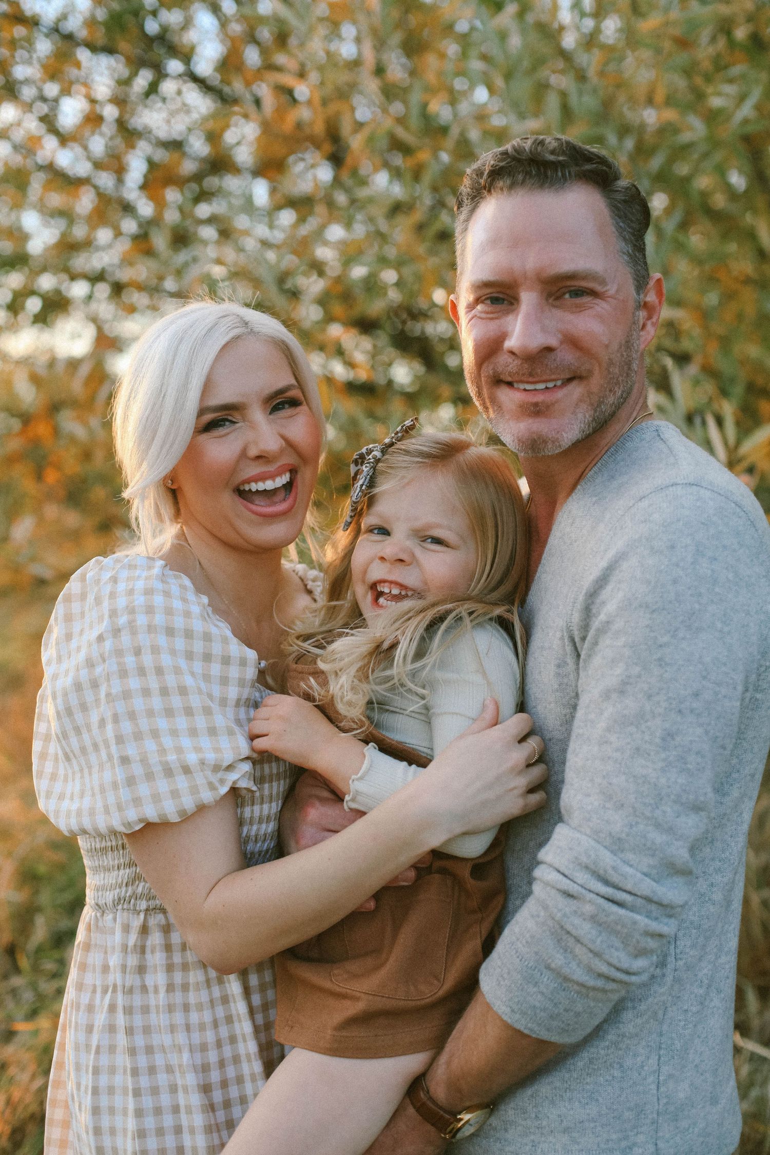 Happy family embracing outdoors during autumn with fall foliage in background.