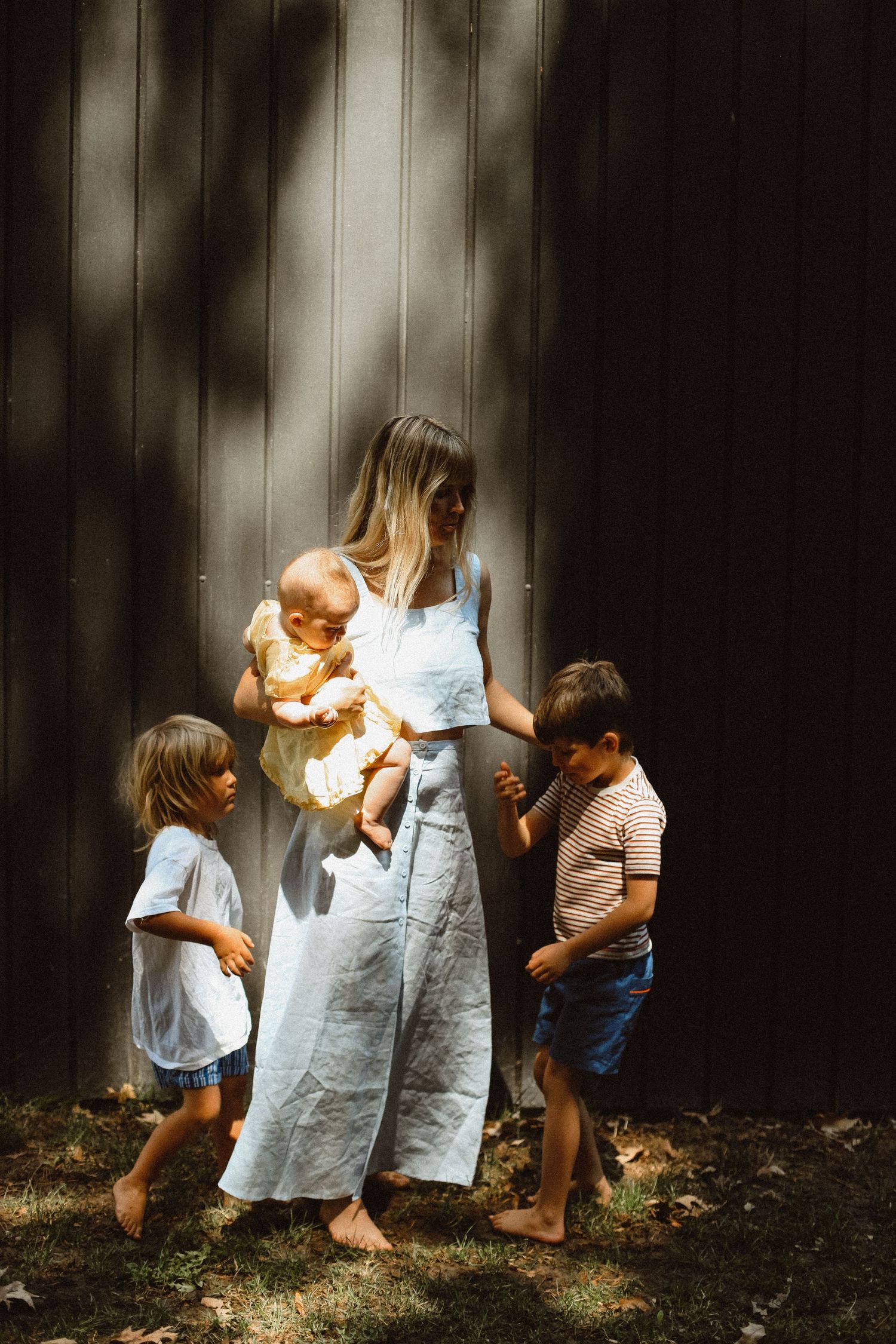 Mother with three children standing against wall with dramatic shadow patterns.