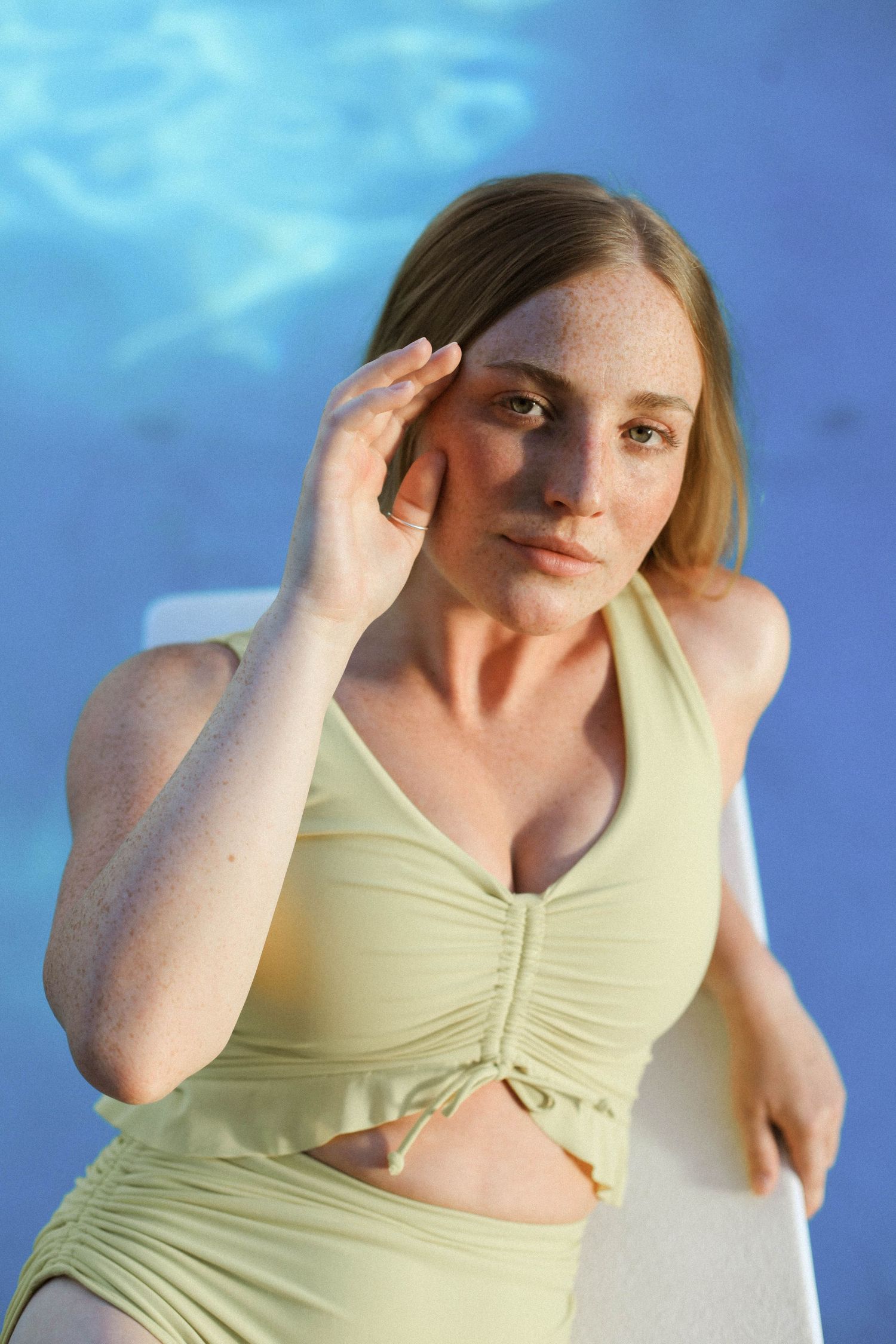 Woman in yellow crop top poses against blue projected background.