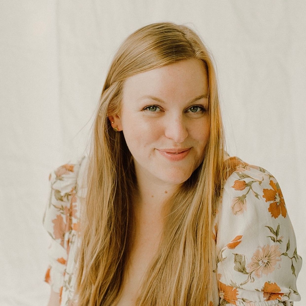 Portrait against white background wearing floral dress.