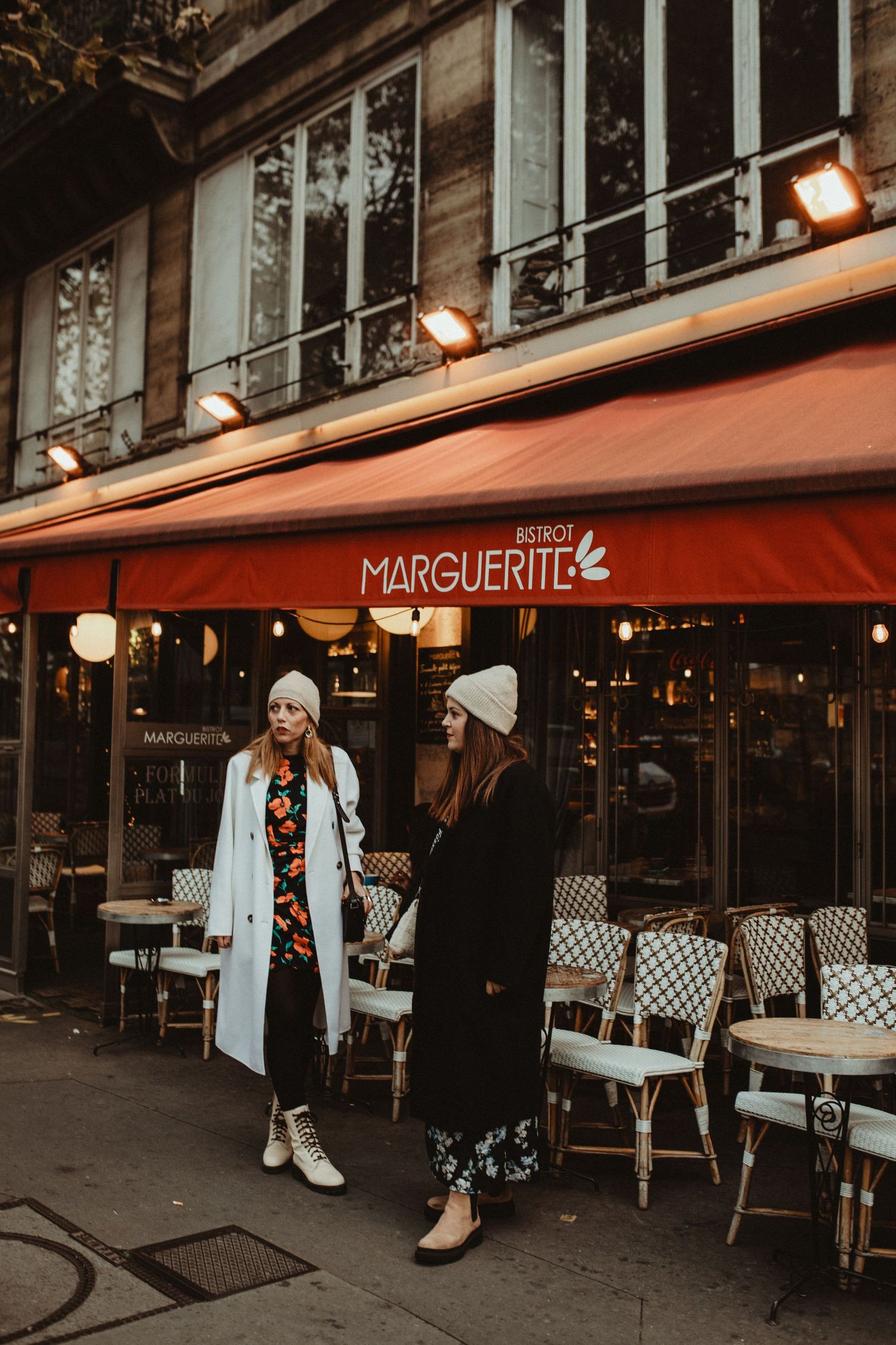 Cozy Parisian bistro Marguerite with outdoor seating and red awning during golden hour.