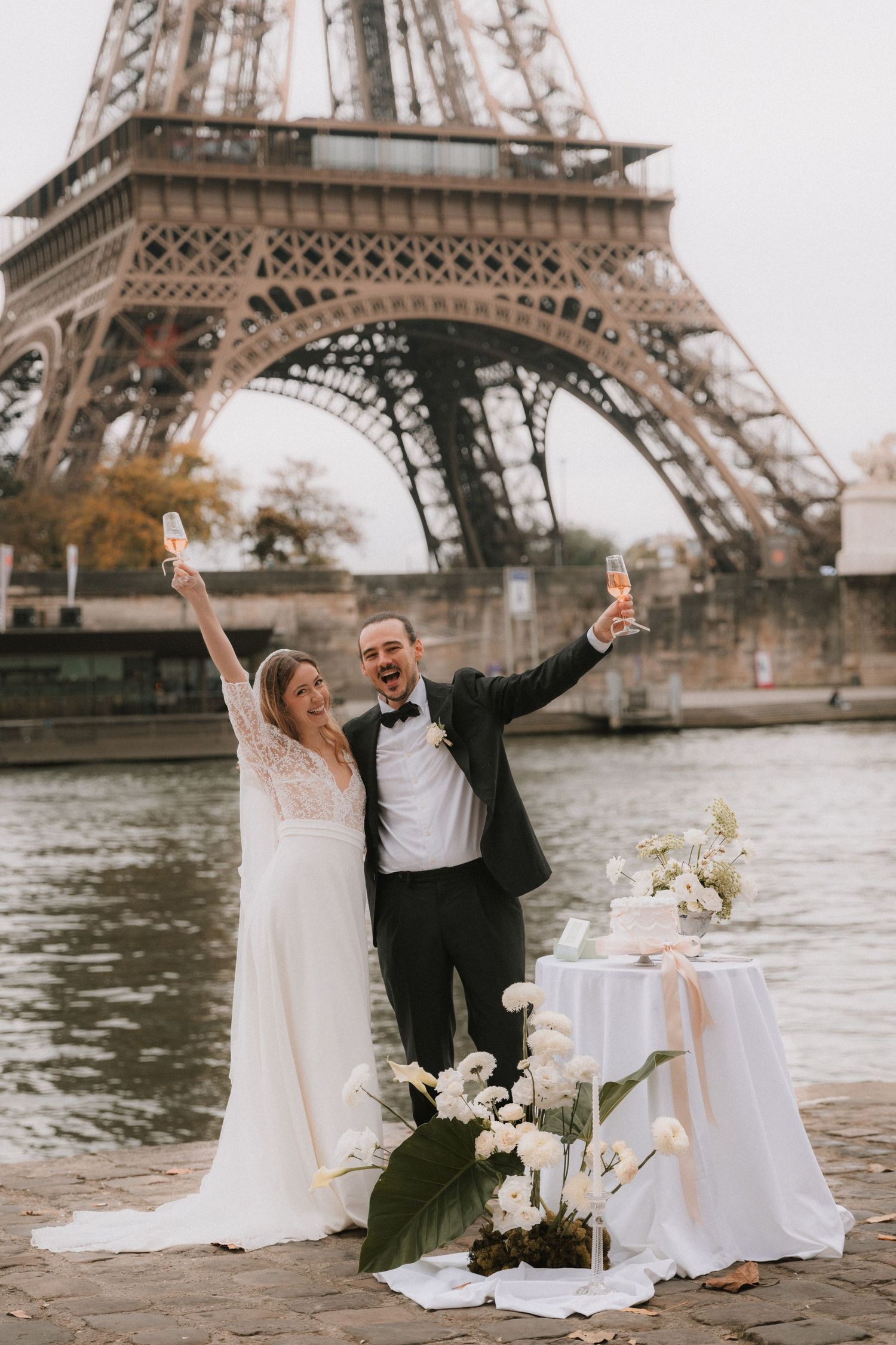Couple celebrates their wedding day with champagne near the Eiffel Tower in Paris with elegant floral decorations.