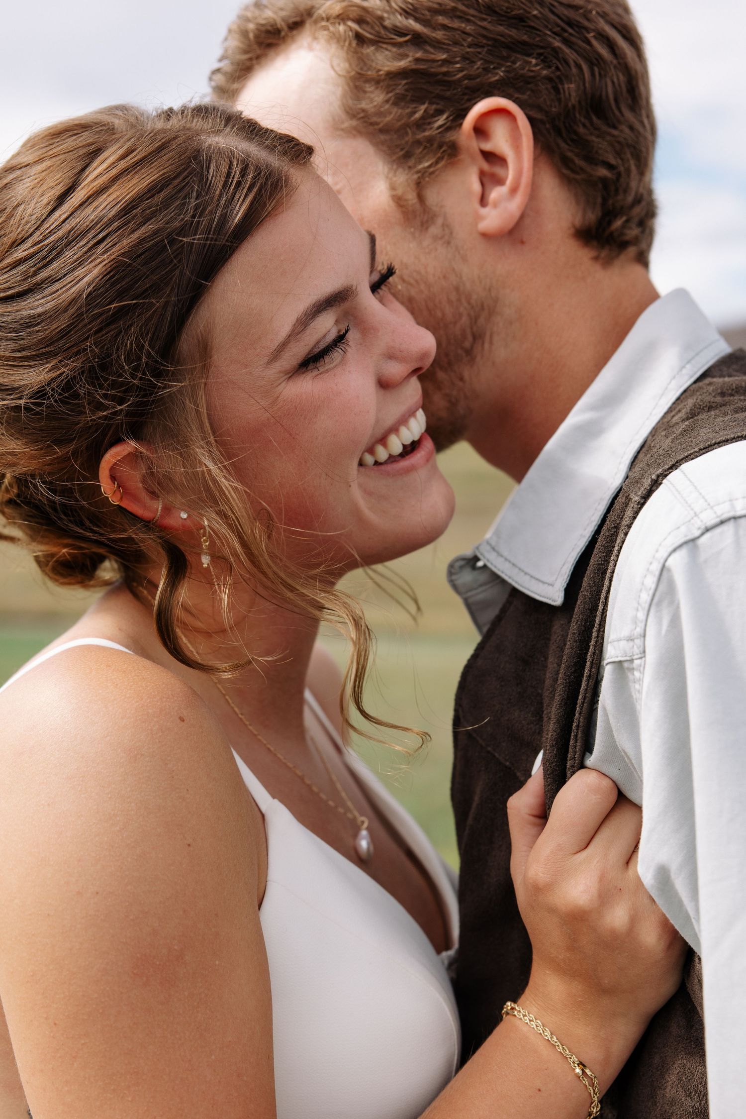 An intimate close-up of a joyful wedding couple sharing a tender moment outdoors.
