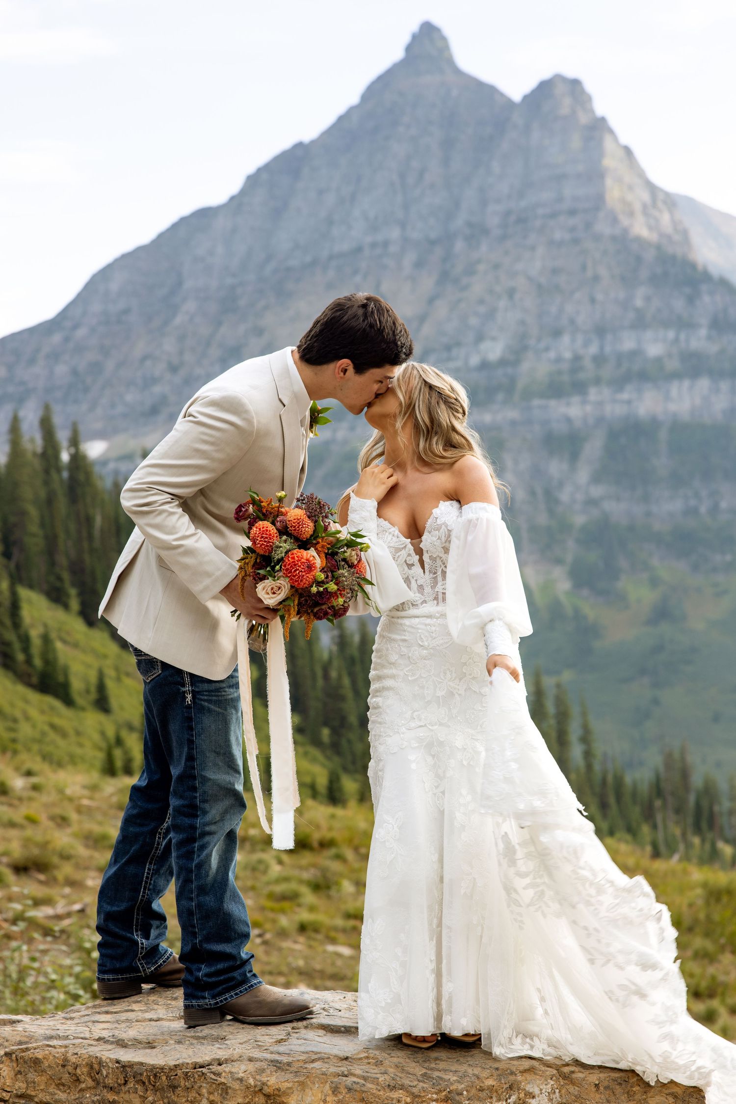A romantic wedding photo with majestic mountain peaks rising in the background at Glacier National Park.