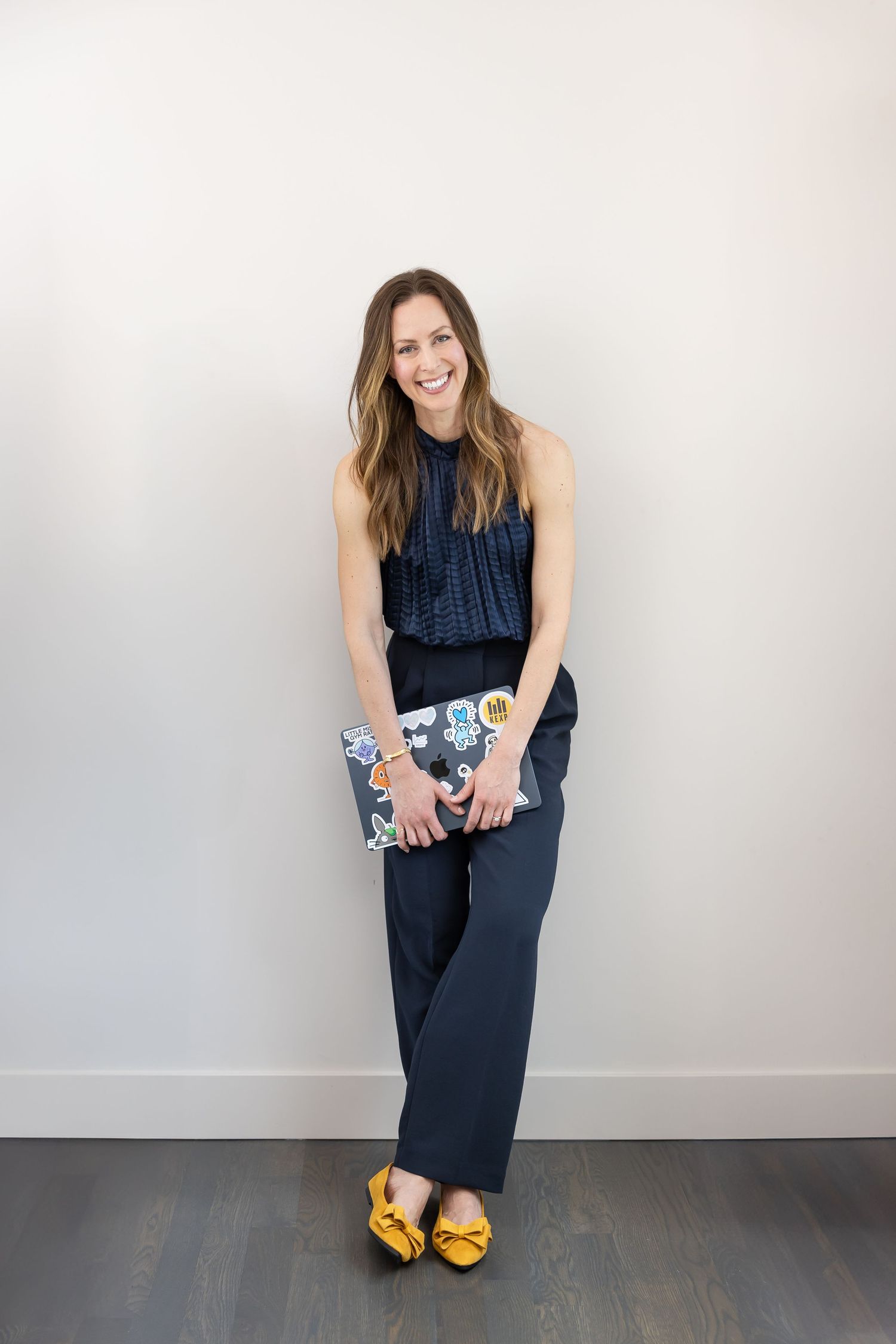 Jessica Stegner Seattle SEO consultant lifestyle headshot standing against wall with computer in hands smiling for branding