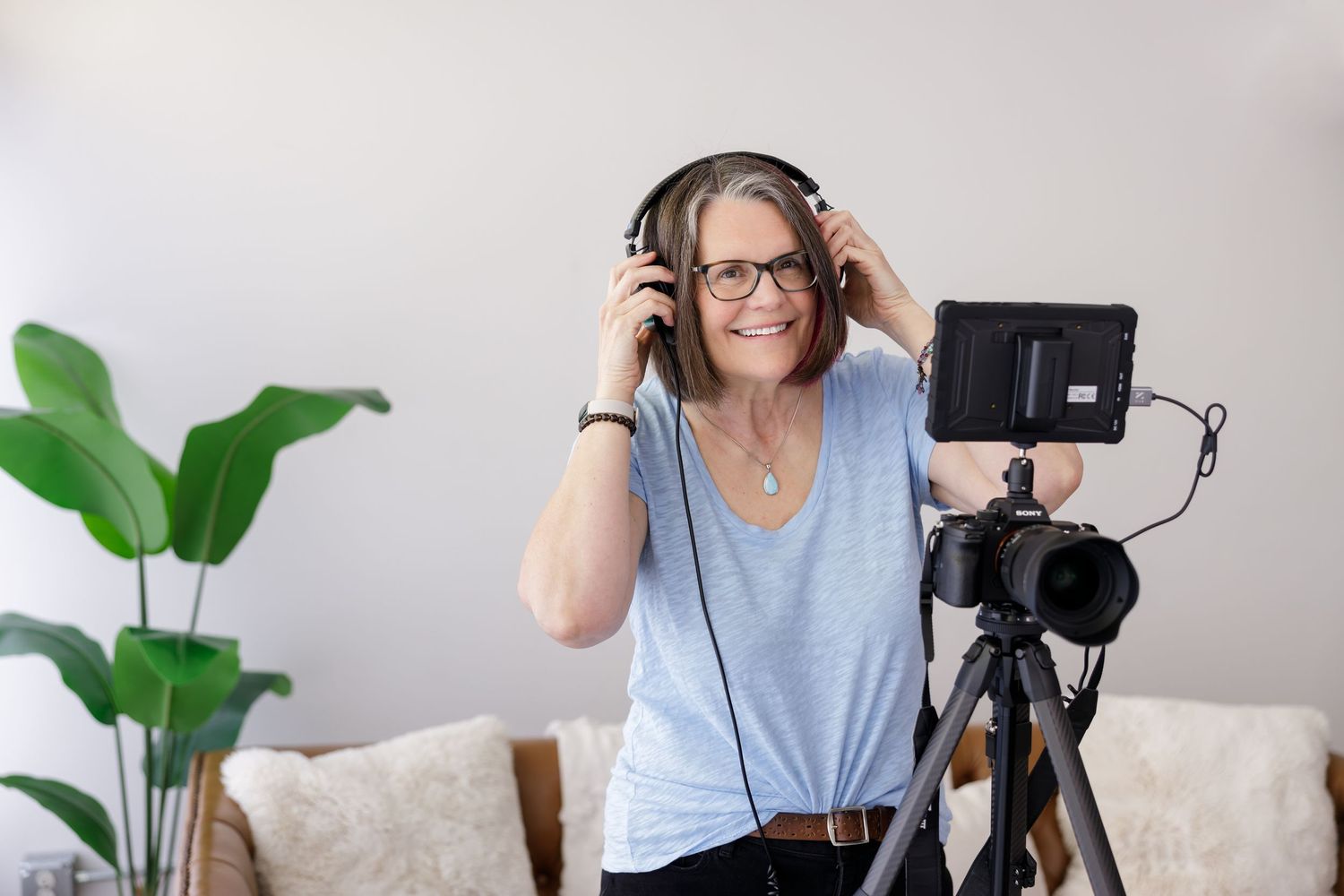 woman videographer business owner standing behind camera putting on headphones for lifestyle personal branding photo in Bothell, WA