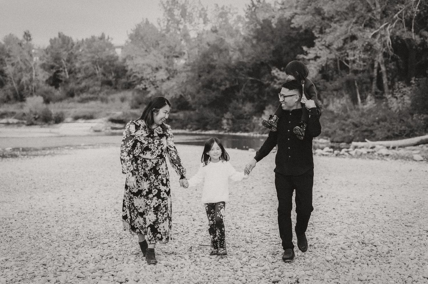 A family holds hands while walking together on a rocky shore.