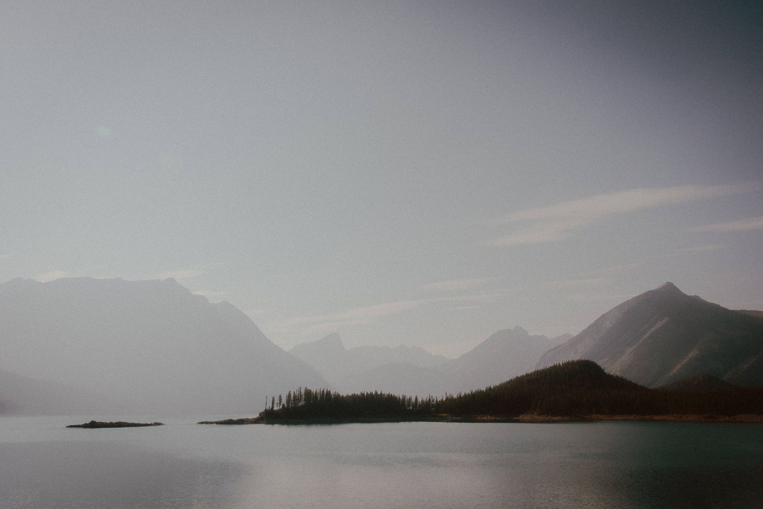 Misty mountain landscape overlooking a serene lake with islands in the distance.
