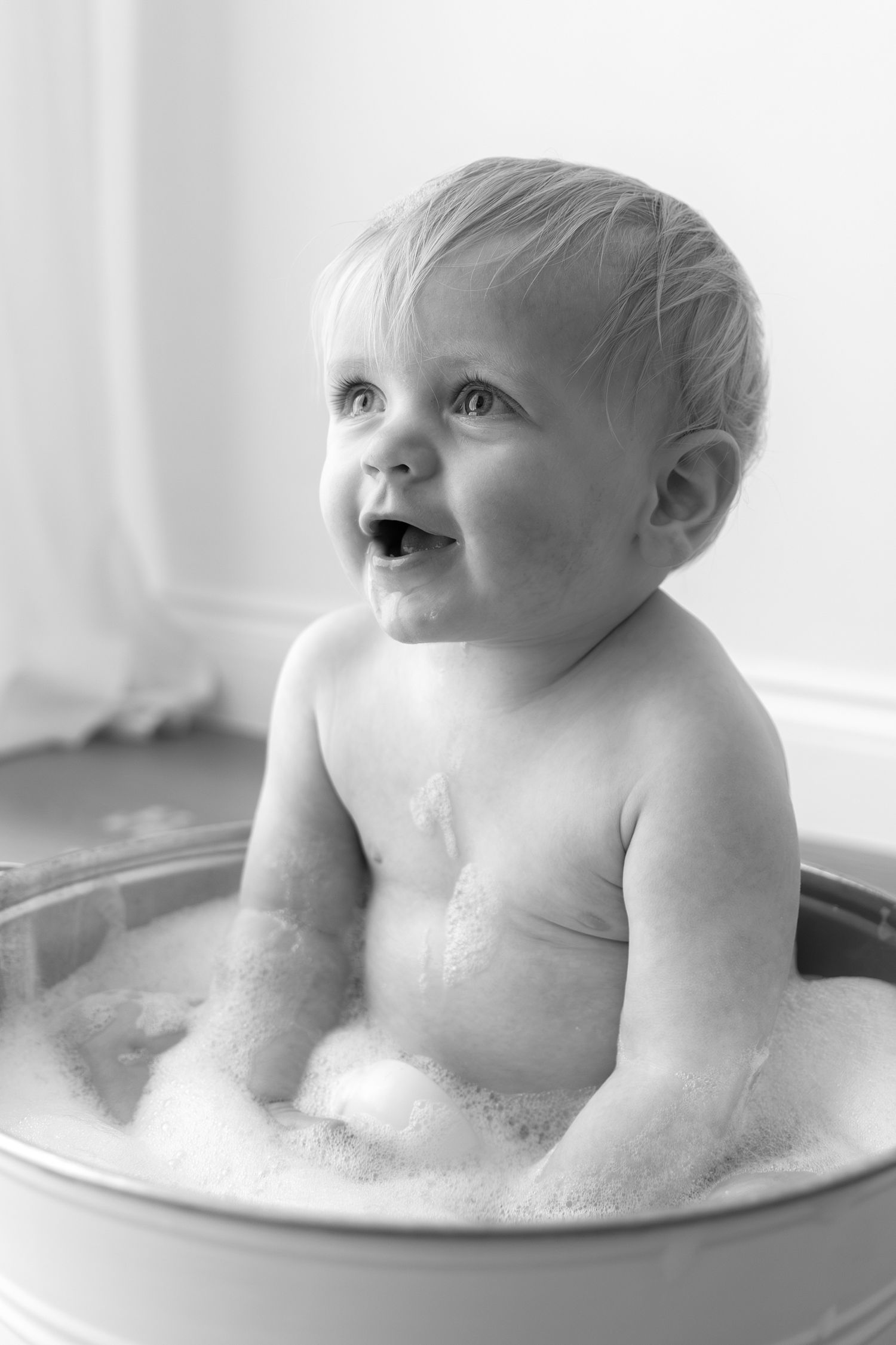 Black and white photo of happy baby taking a bubble bath.