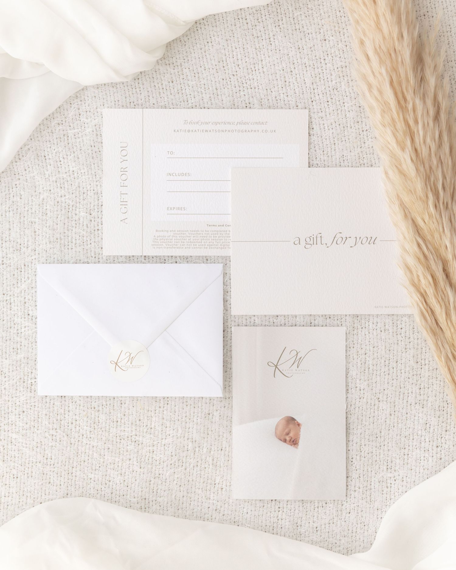Elegant wedding invitation suite in white and beige with pampas grass and wax seal on textured fabric background.