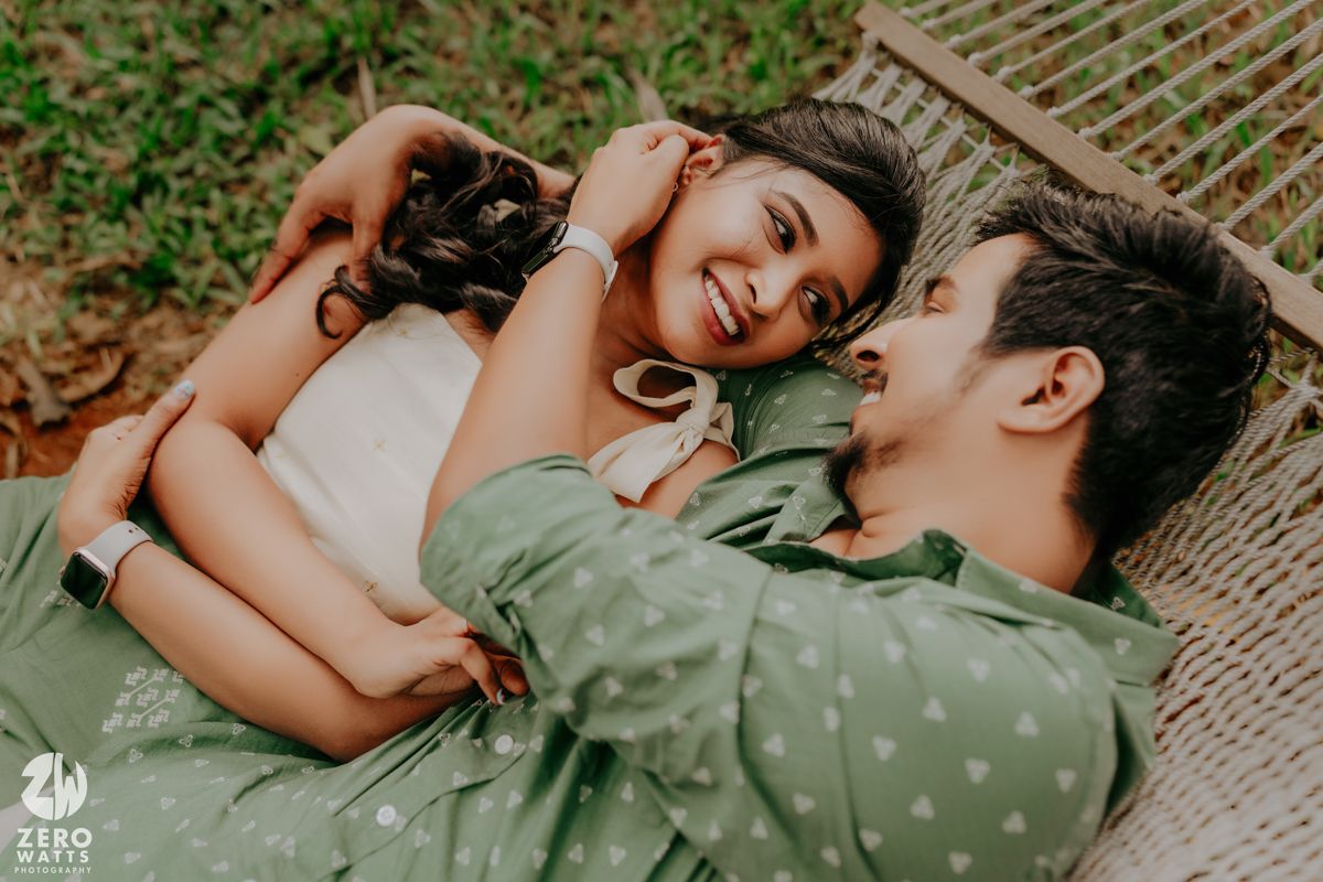Two people share a tender moment lying together in a hammock among green trees and nature.