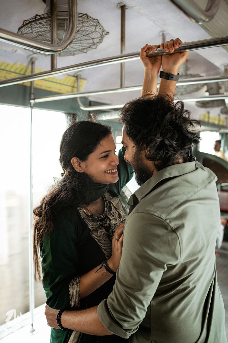 A romantic couple share an intimate moment while holding onto a handrail in a train compartment.