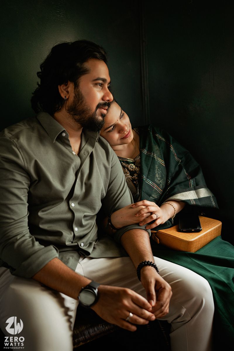 Intimate moments captured in moody lighting as couple sits close together on train seat.