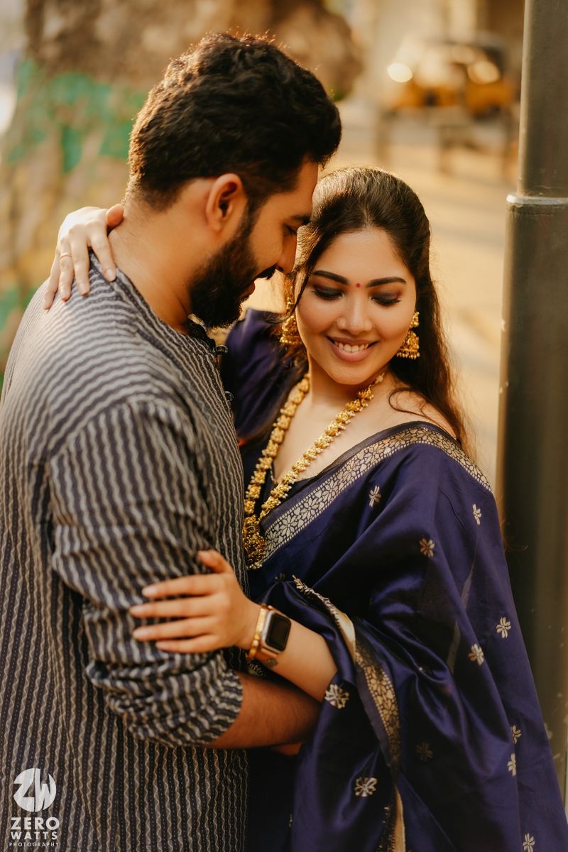 A couple in traditional Indian attire share an intimate moment outdoors in warm lighting.