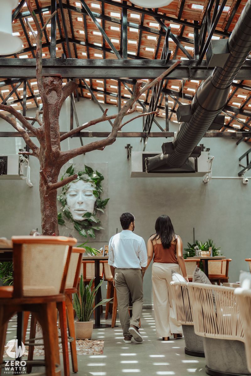 A couple admiring wall art in a modern restaurant with rustic wooden beams.