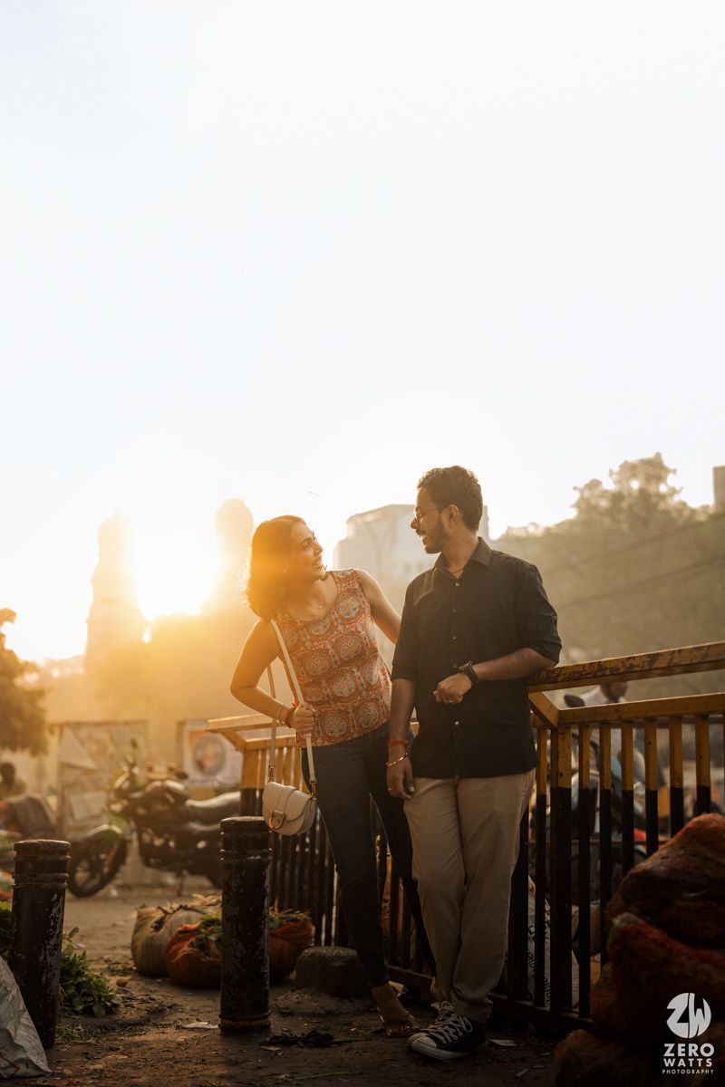 Couple enjoying conversation on balcony during golden hour sunset.
