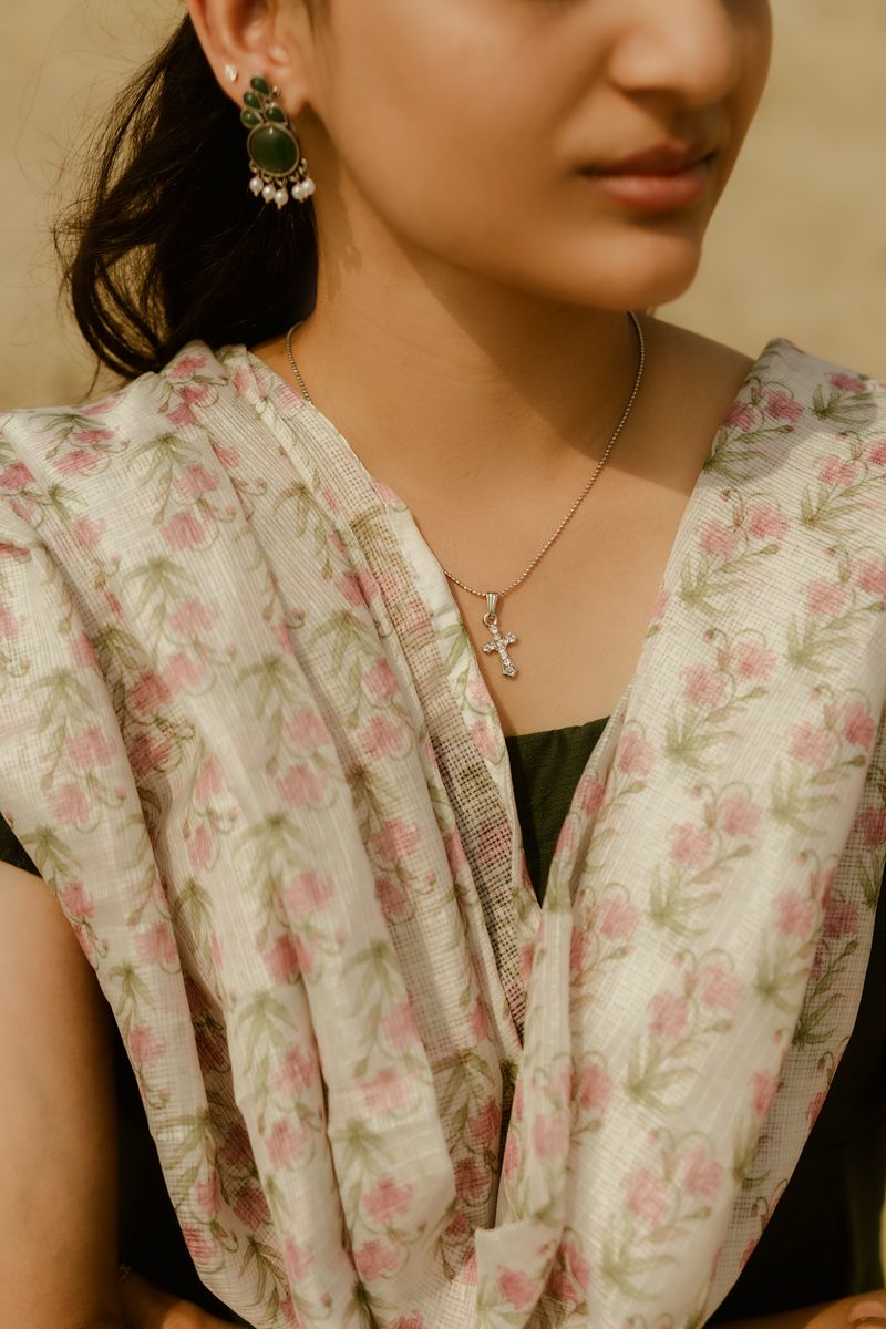 A close-up shot shows delicate floral printed fabric and elegant jewelry including chandelier earrings and a pendant necklace.