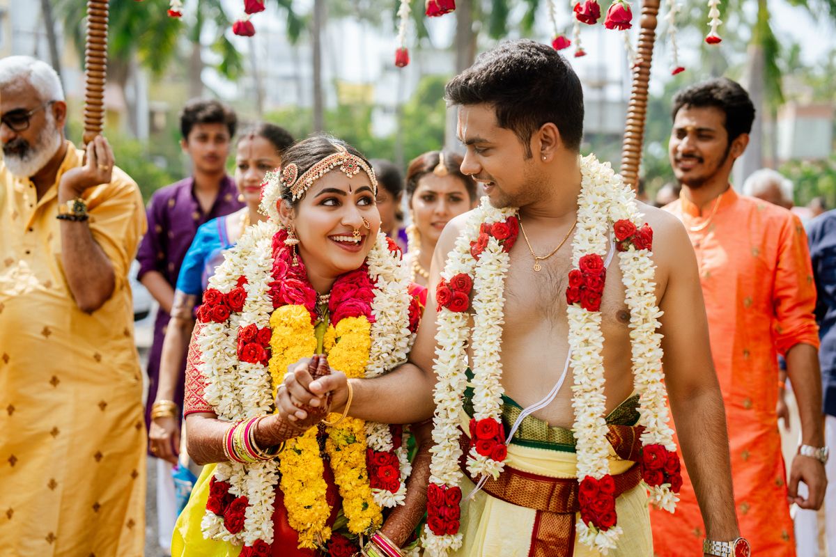 Traditional Indian wedding ceremony with bride and groom wearing colorful floral garlands during a festive celebration.