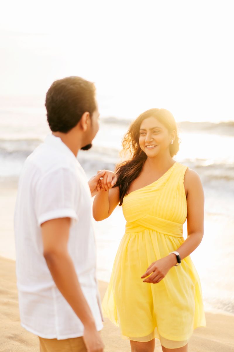 Romantic beach scene with couple in white and yellow outfits during sunset.