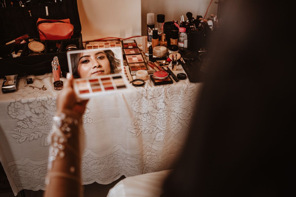 Various makeup products and cosmetics arranged on a white lace tablecloth under dramatic lighting.