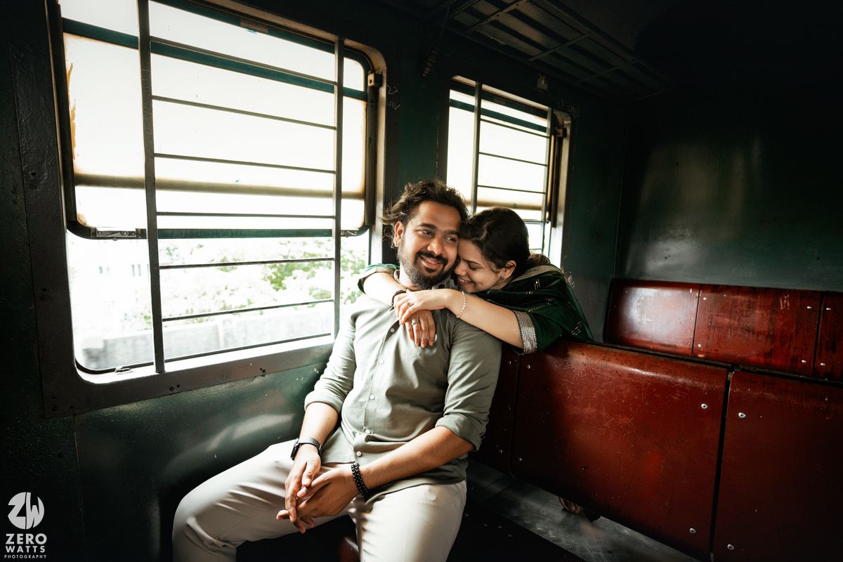 Tender embrace captured in moody lighting inside vintage train compartment.