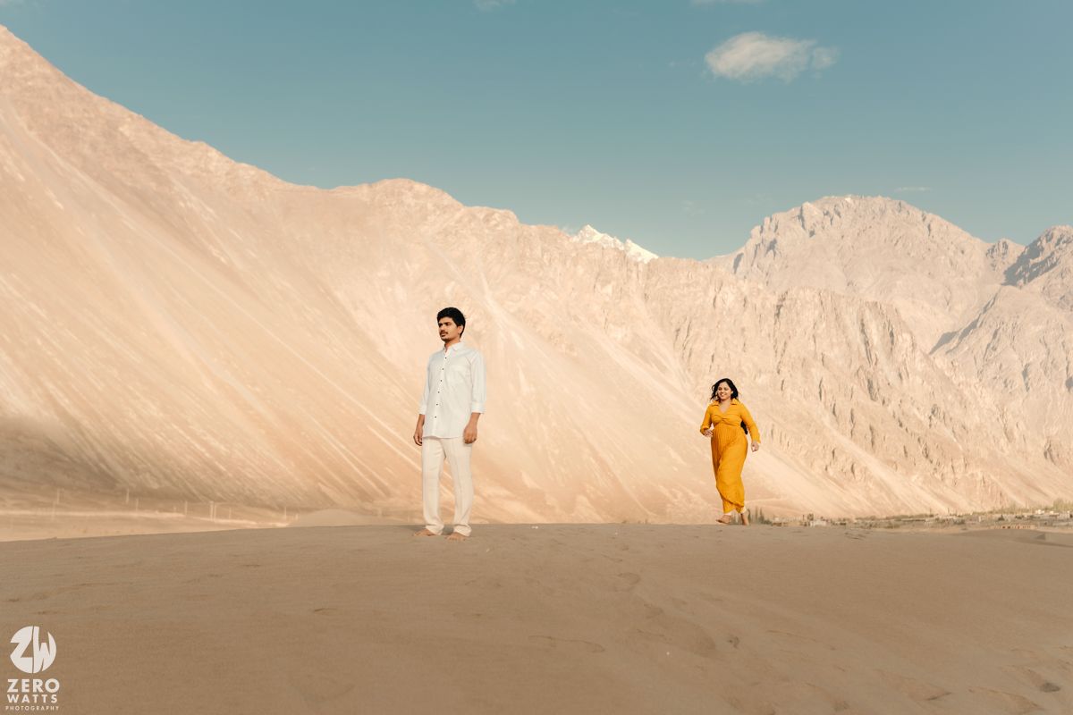 Minimalist desert landscape series featuring distant figures against sandy dunes and clear blue sky in warm tones.