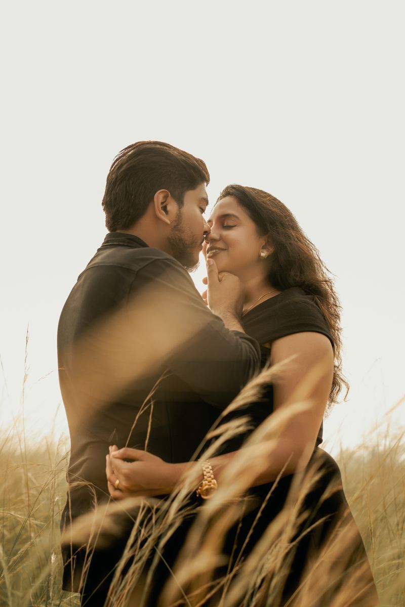 Couple embracing in a golden wheat field during sunset creating a romantic atmosphere.