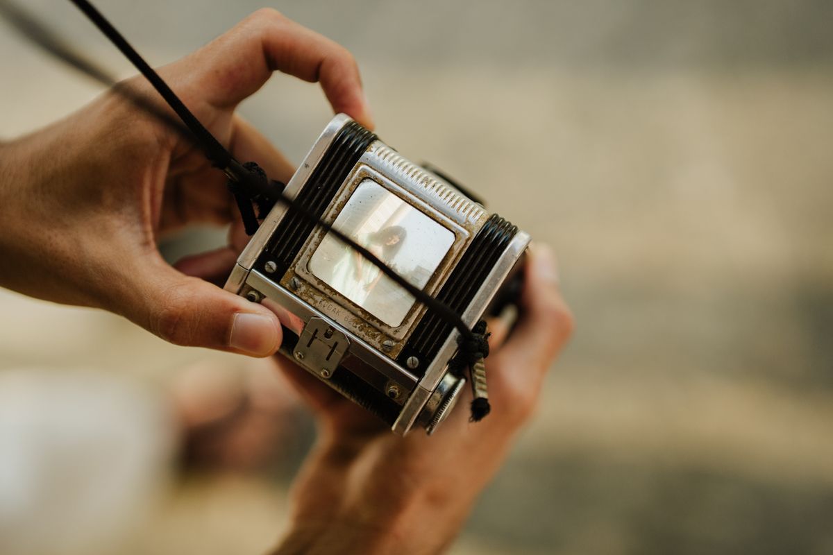 Close-up shot of hands holding and adjusting a vintage twin-lens reflex camera.