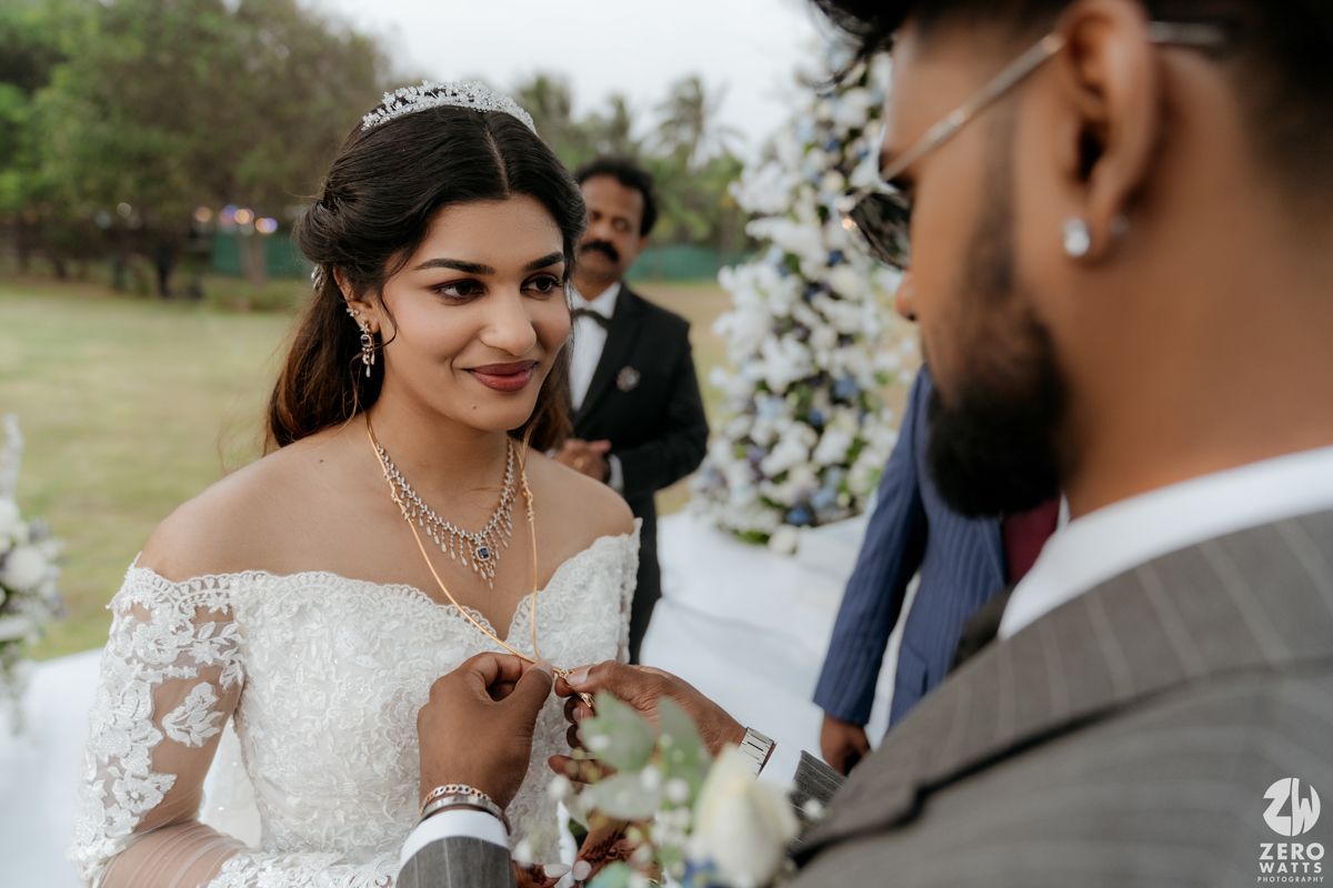 An intimate moment during an outdoor wedding ceremony with delicate lace details and floral decor.