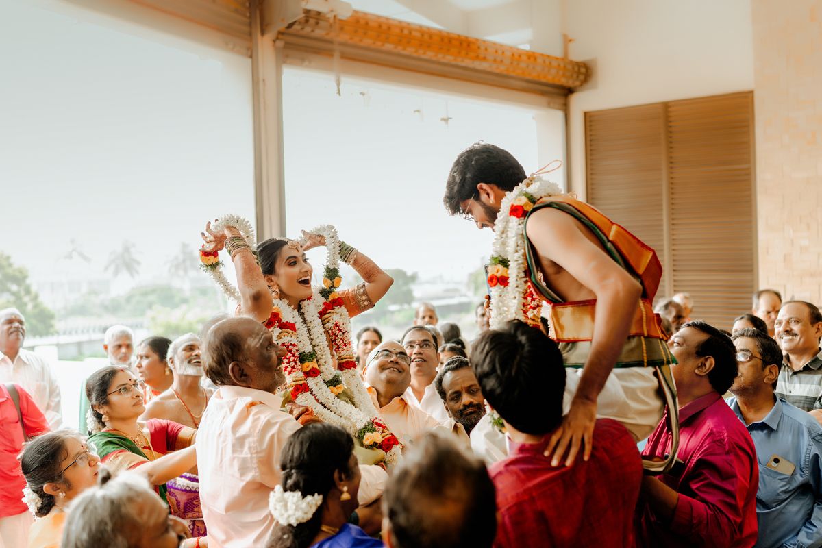 Celebratory crowd lifts and carries guests during festive Indian wedding celebration.