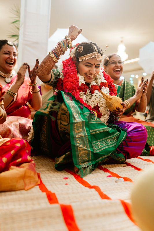A joyous wedding celebration features vibrant traditional Indian attire with red and green saris and cultural ceremonies.