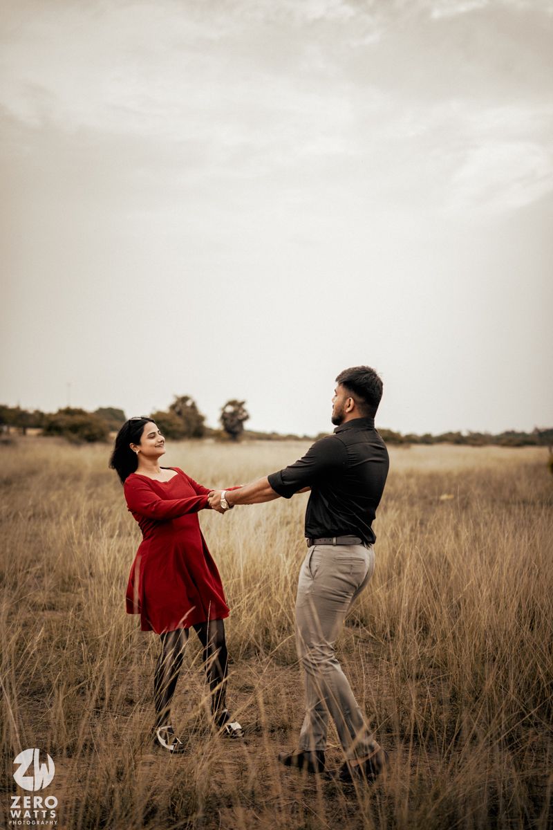 Couple dancing in a sepia-toned field during golden hour.