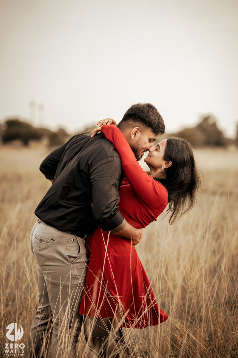 Romantic couple embracing in a wheat field during golden hour.