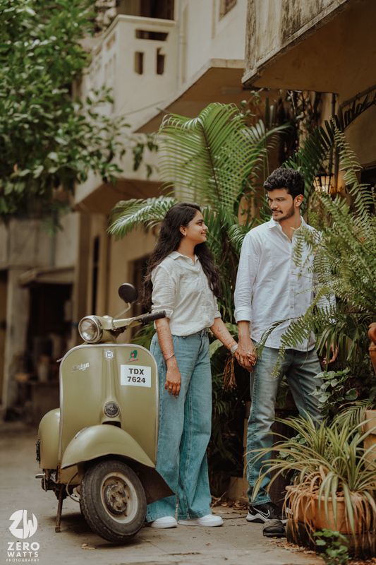 A romantic photoshoot featuring a vintage Vespa scooter among lush garden plants.