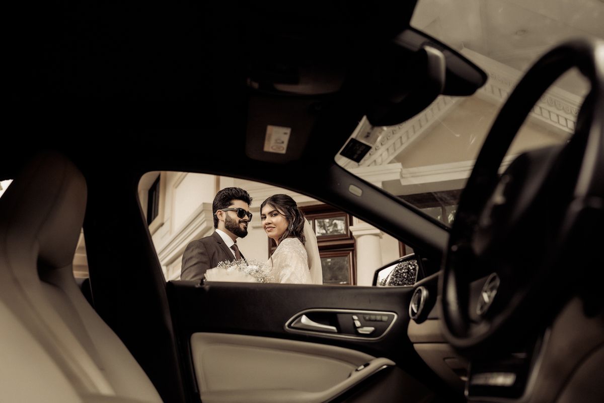 View through car window of couple sitting in parked vehicle in sepia toned photo.