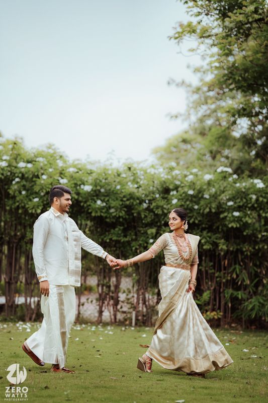 Traditional wedding couple twirling and dancing on a green lawn.