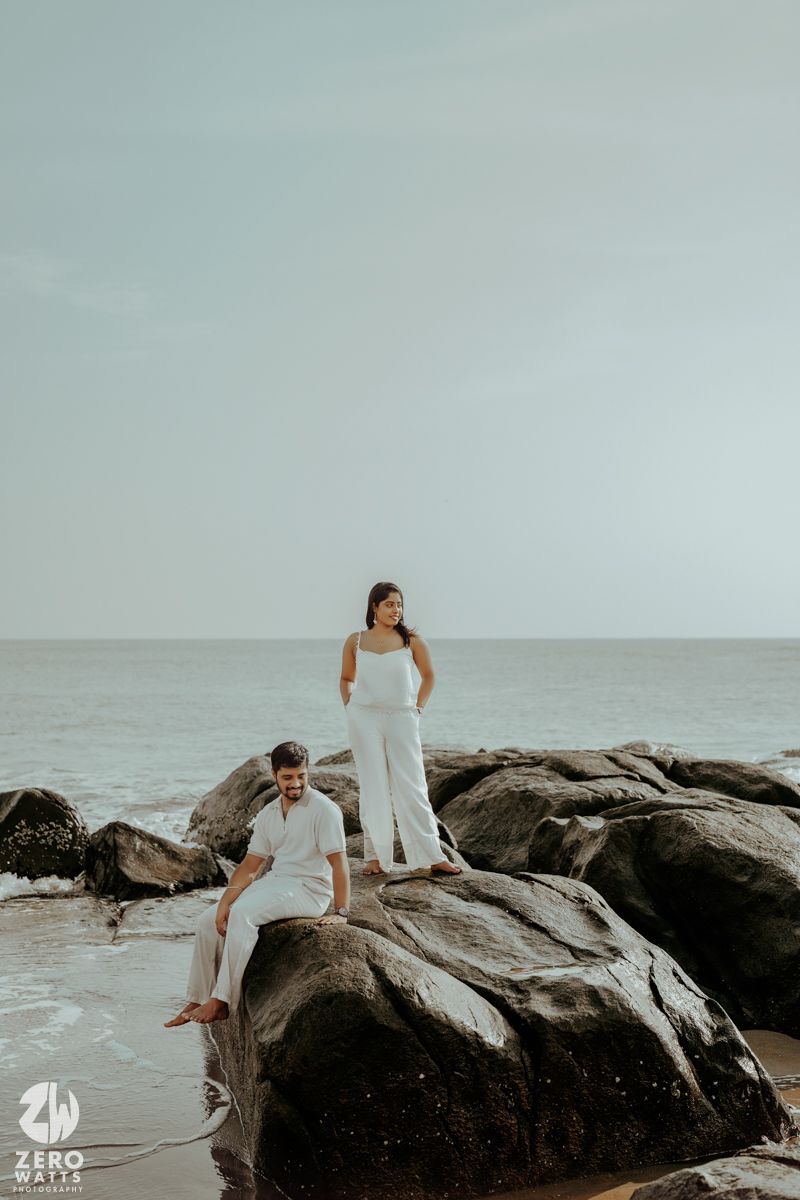 Dreamy coastal photoshoot on rocky beach with misty ocean backdrop.