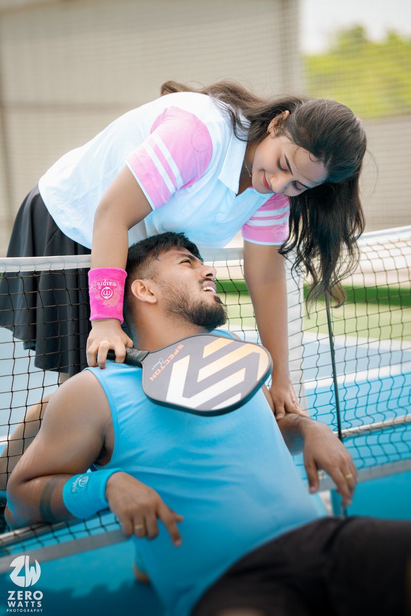 Pair in athletic wear sharing a tender moment on a blue tennis court.