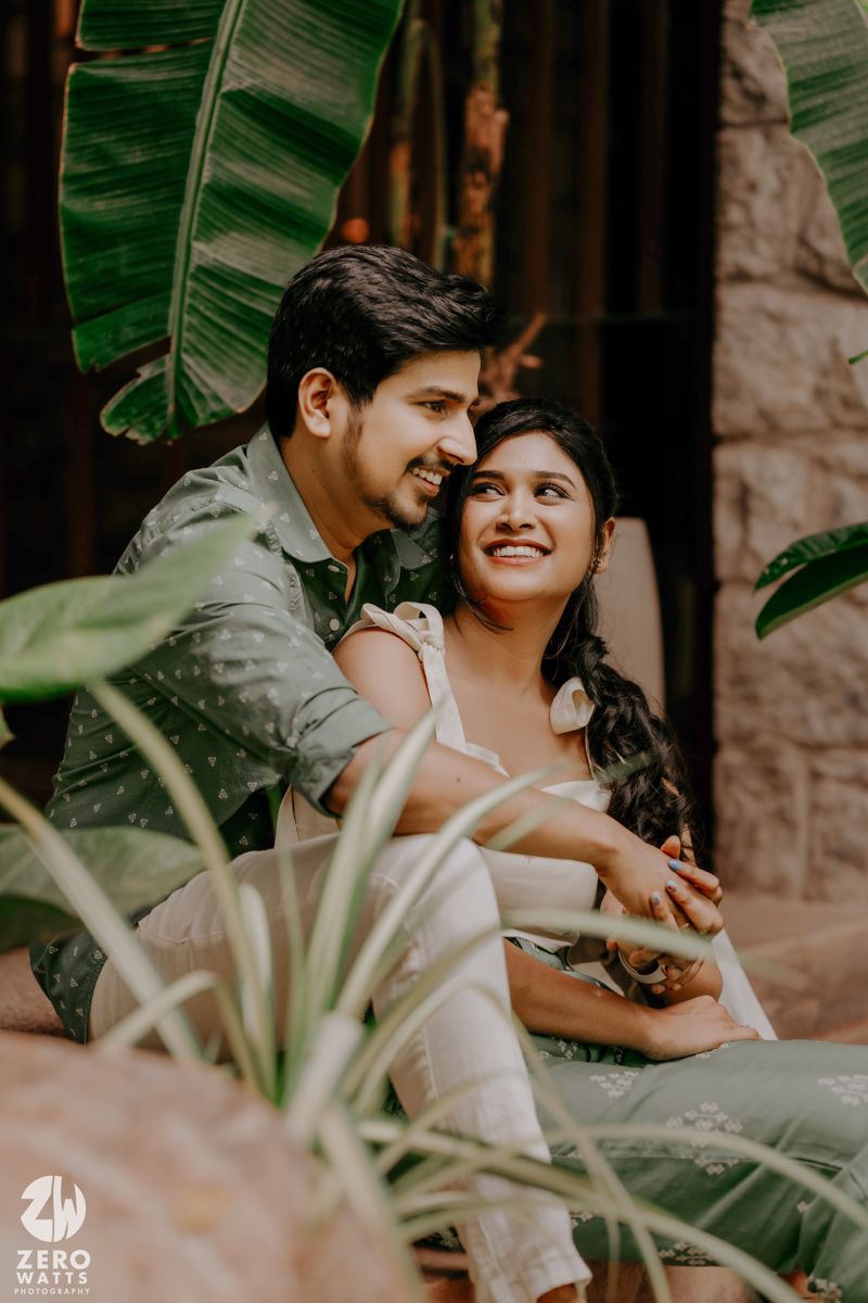 A romantic couple shares tender moments in a tropical garden setting with banana leaves in the background.