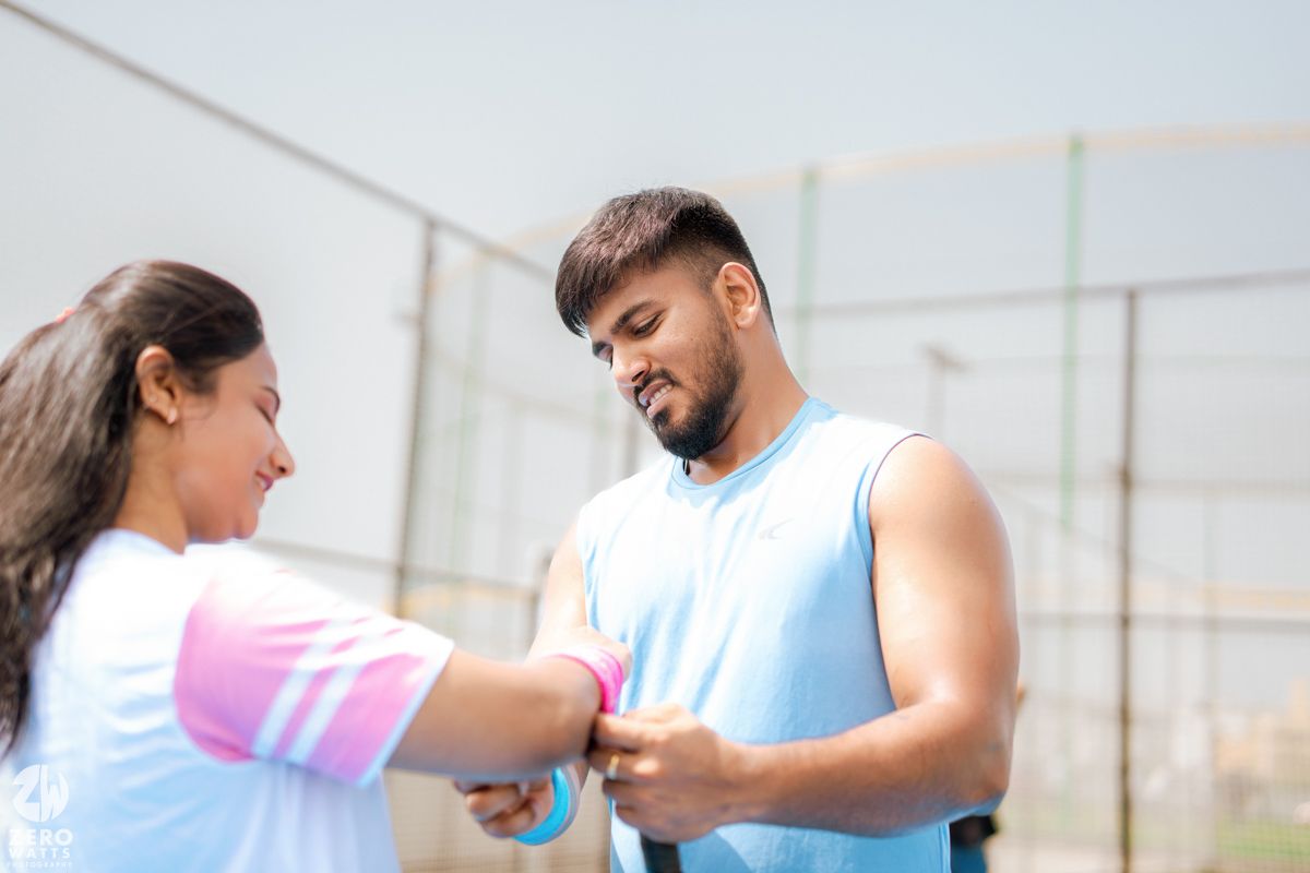 Two people sharing a playful moment on a tennis court with blue flooring.