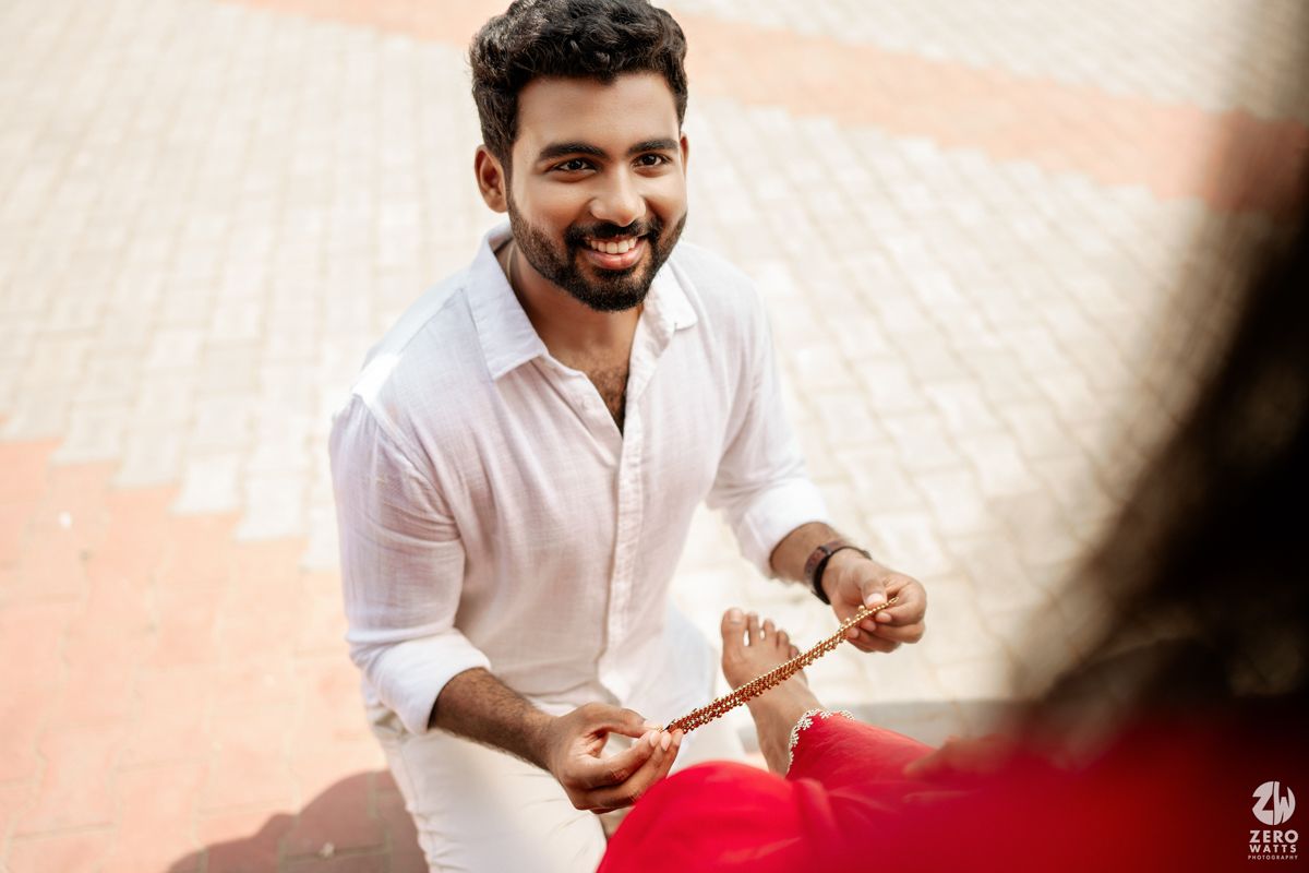 A person in white clothing smiling during what appears to be a traditional ceremony.